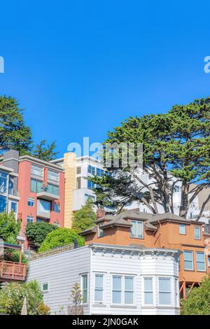 Dichtes Gehäuse in einem schrägen Viertel in San Francisco, Kalifornien. Es gibt Häuser an der Vorderseite mit bemalten Holzverkleidungen gegen die Häuser am Stockfoto