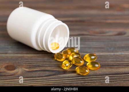 Weiche Geltabletten mit Omega-3-Öl, das aus der Pillenflasche aus der Nähe verschüttet wird. Gelkapseln Flasche weiße Oberfläche. Omega 3, Multivitamine, Kalzium, Antibiotika Stockfoto