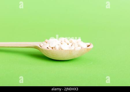 Haufen weißer Pillen auf farbigem Hintergrund. Tabletten auf einem Tisch verstreut. Haufen roter weicher Gelatinekapsel. Vitamine und Nahrungsergänzungsmittel Konzept. Stockfoto