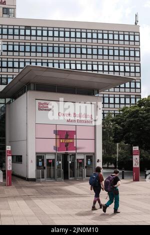 Zwei Personen gehen am Haupteingang des Owen-Gebäudes an der Sheffield Hallam University am Arundel Gate vorbei Stockfoto