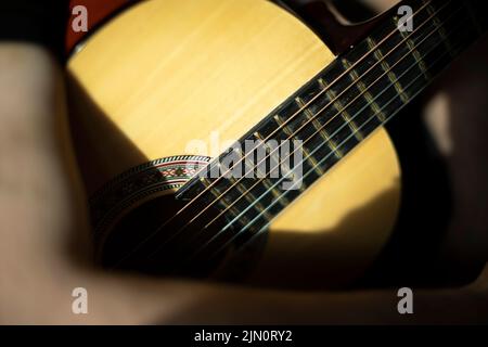 Akustische Gitarre mit sechs Saiten. Alte Gitarre im Sonnenlicht. Details des Musikinstruments. Stockfoto