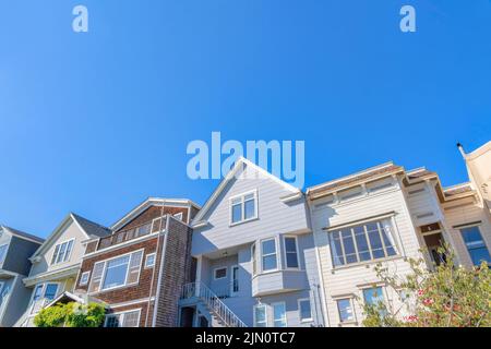 Fassade von Gewächshäusern in San Francisco, Kalifornien gegen den Himmel. Rowhouses außen mit Treppen zu den Vordertüren und Wänden mit verschiedenen k Stockfoto