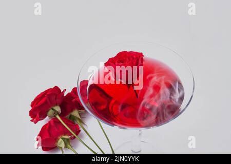 Nahaufnahme von roten Cocktails und Rosenblüten. Isoliert auf weißem Hintergrund. Stockfoto
