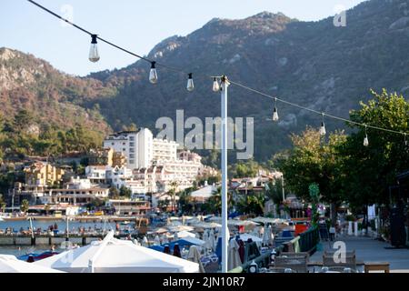 Straßenlaternen auf dem Damm und der Promenade des Feriendorfes. Kleine Stadt, umgeben von Bergen. Verschwommenes und unscharf fokusstes Bild Stockfoto