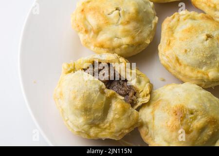 Mini-Steak Pie auf Teller, offen geschnitten, mit ganzen Gebäckstücken Stockfoto