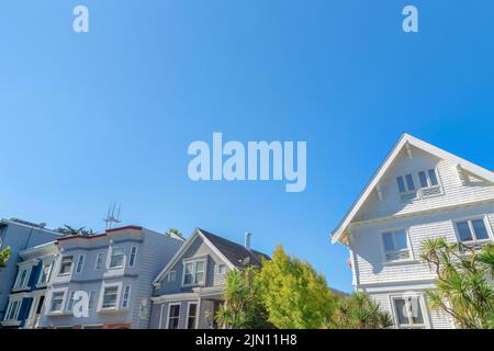 Blick auf die Fassade der Häuser von unten gegen den klaren blauen Himmel in San Francisco, CA. Auf der linken Seite befinden sich zwei Häuser mit flacher Dachkonstruktion Stockfoto