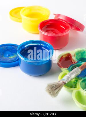 Nahaufnahme von geöffneten Gouache-Farbgläsern und Acrylfarben, mit Pinsel und Palette, isoliert auf weißem Hintergrund, Weichfokus mit Kopierbereich Stockfoto