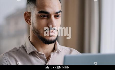 Nahaufnahme männlich Porträt ruhig arabisch Geschäftsmann Kerl hispanic Mann freiberuflicher Web-Designer tippt SMS-E-Mail auf Laptop zu Hause Büro verwenden persönlich Stockfoto