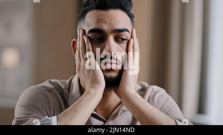 Depressiv müde hispanic arabischen Mann Kerl Geschäftsmann Arbeiter sitzen zu Hause fühlen Langeweile Depression massieren Gesicht Stirn leiden an Schlaflosigkeit denken Stockfoto