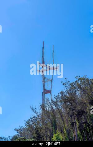 Blick auf den Gipfel des Sutro Tower von unten in San Francisco, CA. Es gibt Bäume an der Vorderseite unter dem Turm gegen den klaren blauen Himmel auf der Rückseite Stockfoto