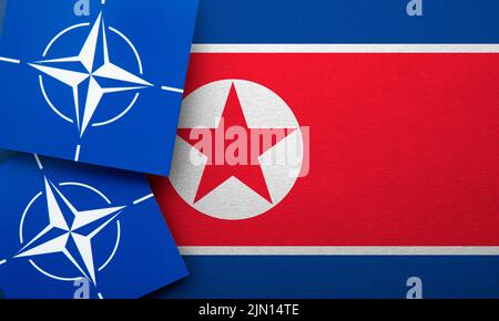 LONDON, Großbritannien - 2022. August: Logo der NATO-Organisation für den Nordatlantikvertrag für ein Militärbündnis auf einer nordkoreanischen Flagge Stockfoto