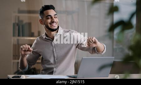 Glücklich lustig männlich arabisch Geschäftsmann hispanic jung Kerl tausendjährig lächelnd Mann aktiv tanzen zu Hause Büro hat Spaß feiern Ende der Arbeit genießen Stockfoto