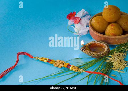 Rakhi für das indische Festival von raksha bandhan mit süßem Laddu, Öllampe Diya und anderen heiligen Zutaten während der Feier. Stockfoto