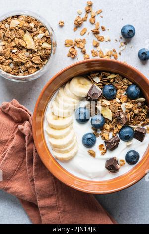 Joghurt-Müslischale mit Heidelbeeren, Banane und Schokolade. Draufsicht Stockfoto