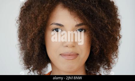 Extreme Nahaufnahme Kopfschuss weiblich Serious ruhiges Gesicht mit perfekter Haut natürliches Make-up Afrikanische Biracial Model Frau mit lockigen Haaren Blick auf die Kamera Stockfoto