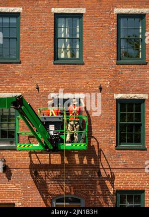 Bauarbeiter installieren neue Fenster an einem Mühlengebäude in der Innenstadt von Bideford Maine Stockfoto