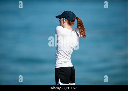 Das Bild einer Frau, die sich vor ihrem morgendlichen Strandlauf streckt. Nächstplatzierter Wärmt Sich Auf, Beach Runner, San Francisco, Kalifornien, Gesundheit, Wellness, Sport Stockfoto