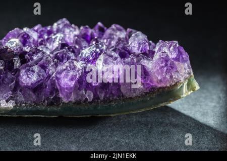 Lila Amethyst Druse Kristalle Edelstein Cluster auf schwarzem Hintergrund. Makroaufnahme in extremer Nahaufnahme. Stockfoto