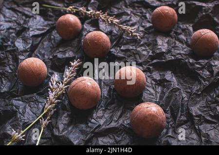 Schokolade runde Süßigkeiten dunkel zerknittertes Bastelpapier mit Lavendelblüten Stockfoto