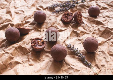 Schokoladen-Bonbons auf braunem zerknittertem Bastelpapier mit Lavendelblüten Stockfoto