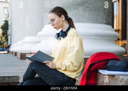 Positive tägliche Affirmationen für die Selbstliebe. Junge Frau mit Kopfhörern, die in einem Notebook schreibt Stockfoto
