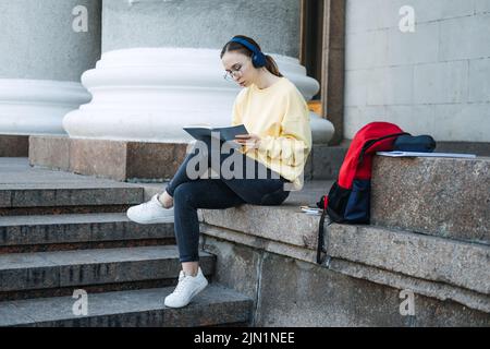 Positive tägliche Affirmationen für die Selbstliebe. Junge Frau mit Kopfhörern, die in einem Notebook schreibt Stockfoto