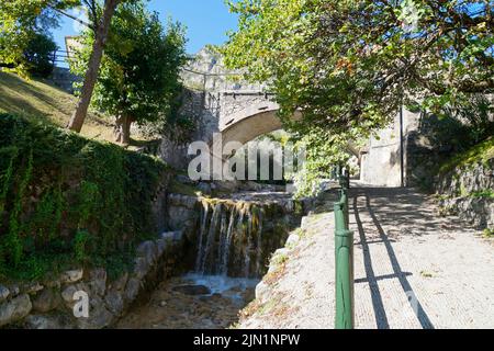 Eine alte Steinbrücke über den Bach San Giovanni (Torrente San Giovanni) in der wunderschönen grünen italienischen Stadt Limone sul Garda am Gardasee (Italien Stockfoto