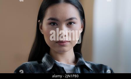 Close-up nachdenklich ruhigen weiblichen Gesicht mit perfekten natürlichen Make-up Hautpflege Service Kunde Versicherungshaus Besitzer Asian 20s Frau Blick auf die Kamera Stockfoto