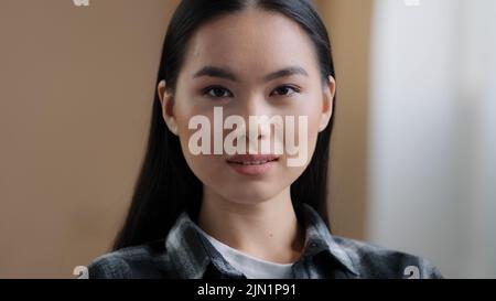 Selbstbewusst 20s Mädchen 30s asiatische ethnische Frau perfekte Haut Gesicht Blick auf Kamera posiert allein zu Hause im Büro tausendjährige koreanische Ethnizität Student Stockfoto