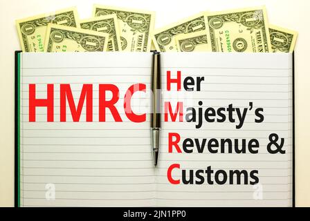 HMRC her majestys Einkommens- und Zollsymbol. Konzept Worte HMRC her majestys Umsatz und Zoll auf weißer Note auf schönen Dollar Hintergrund. Bus Stockfoto