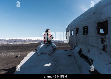 Frau, die auf dem Flügel eines verlorenen Flugzeugs sitzt Stockfoto