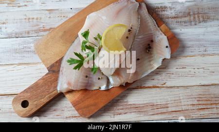 Frisches Tilapia-Fischfilet in Scheiben für Steak oder Salat mit Kräutern, Gewürzen und Zitrone Stockfoto