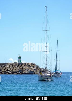 Jachten in der Bucht in der Nähe des Damms mit einem Leuchtturm Stockfoto