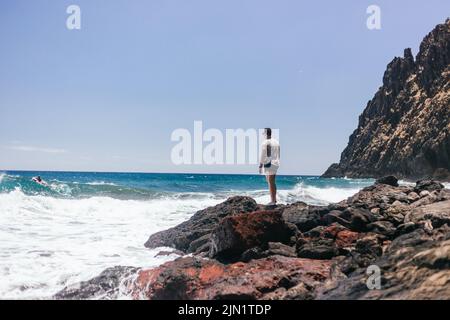 Schöner junger Latein, der an sonnigen Tagen die Landschaft von Felsen aus genießt Stockfoto