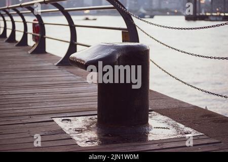 Schwarzer Metallanlegeplatz in Marina und Hafenterminal. Nahaufnahme der Anlegestelle noray auf einem Dock. Stockfoto