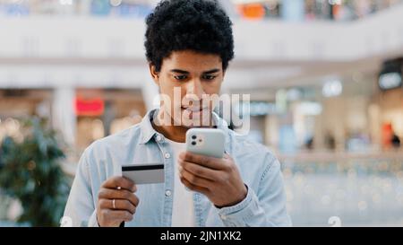 Afrikanischer Dominikaner tut Online-Shopping-Transaktion in net man mit Telefon trägt Kartennummer Probleme mit Finanzfehler in mobile App Stockfoto