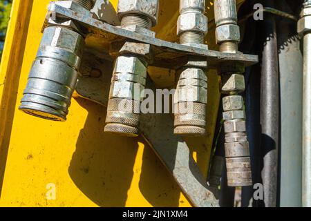 Verschiedene Adapter für Hydraulikschläuche am Schaufelarm eines Radladers zur Befestigung verschiedener Eimer-Typen Stockfoto