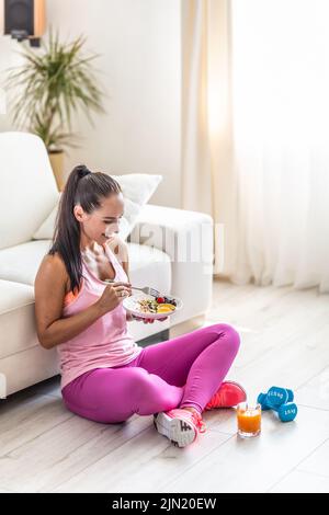 Sportliche junge Frau, die nach dem Training einen Haferbrei mit Beeren und Früchten isst. Stockfoto