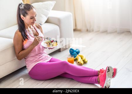 Sportliche junge Frau, die nach dem Training einen Haferbrei mit Beeren und Früchten isst. Stockfoto