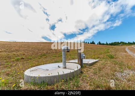 Methan-Standrohr und elliptische und rechteckige Betonblöcke auf einer geschlossenen Deponie, die in einen Park umgewandelt wurde. Stockfoto