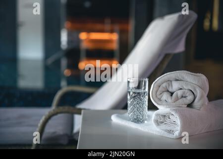 Spa-Hintergrund mit einem Glas Wasser und Handtüchern in einem Spa-Komplex. Stockfoto