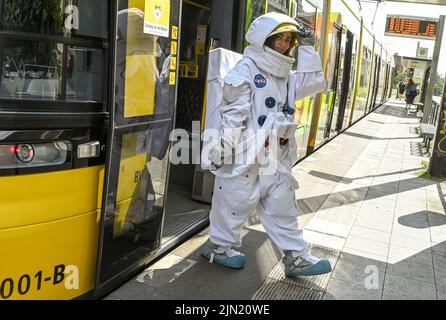 Berlin, Deutschland. 08. August 2022. In einem NASA-Raumanzügen steht die Mitarbeiterin Jana Locher vor dem Zeiss-Großplanetarium Prenzlauer Berg an einer Straßenbahnhaltestelle. Die Aktion lenkt die Aufmerksamkeit auf die lange Nacht der Astronomie 9. am Samstag (Aug 13, 2022) im Tempelhofer Feld. Experten werden mit mobilen Teleskopen vor Ort sein, um Sternfans beim Blick auf den Nachthimmel zu begleiten und Fragen zu beantworten. Quelle: Jens Kalaene/dpa/Alamy Live News Stockfoto