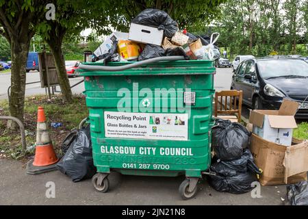 Überfließender Abfalleimer und schwarze Plastiktüten auf einem Bürgersteig, der darauf wartet, geräumt zu werden, Glasgow, Schottland, Großbritannien Stockfoto