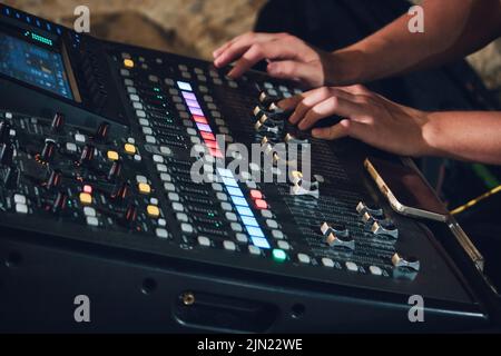 Aufnahme eines Multi-Track-Sound-Mixers für Live-Events mit Händen eines Mannes auf der Konsole, der Fader-Tasten drückt Stockfoto