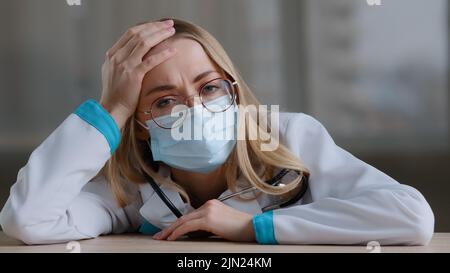 Verärgert traurig müde kaukasische Frau erschöpft überarbeiteten weiblichen Arzt Chirurg Arzt Krankenschwester Praktiker in schützende medizinische Gesichtsmaske Uniform Stockfoto