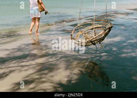 Frau, die am Strand mit einem Schaukelstuhl läuft Stockfoto