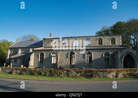 Die Kirche des heiligen Johannes des Evangelisten, Oxborough, Norfolk zeigt das fensterlose, ruinierte Kirchenschiff mit dem intakten Chor links Stockfoto