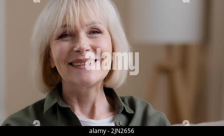 Vorderansicht Porträt reife blonde lächelnde kaukasische Frau Blick auf Kamera posiert im Studio-Porträt, fröhlich ältere grauhaarige weibliche Oma in Stockfoto