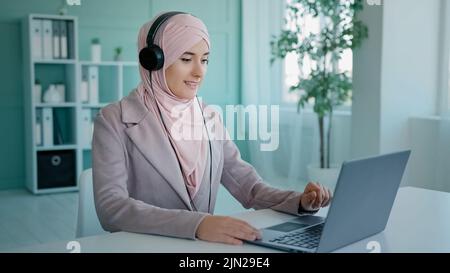 Arabisches Mädchen in rosa Hijab Geschäftsfrau islamische Hilfe Line-Manager muslimische Frau in Kopfhörer Agent des Kunden-Support-Service Videokonferenz in Stockfoto