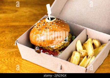 Frische leckere Burger und pommes Frites in Papierkarton auf dem Tisch. Ungesunde Fast-Food-Hamburger. Stockfoto